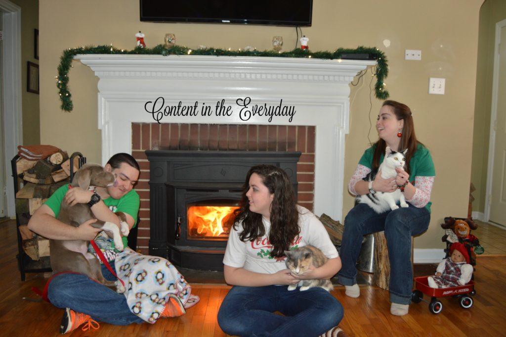 a boy a puppy kissing the boy and two girls holding cats posing for a Candid Christmas card