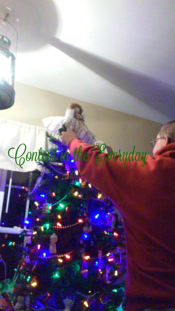 Man putting the Angel on top of the Christmas tree